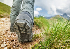 a close-up of a person wearing hiking boots walking on a trail