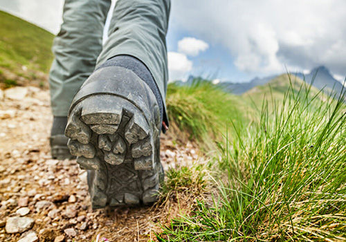 a close-up of a person wearing hiking boots walking on a trail