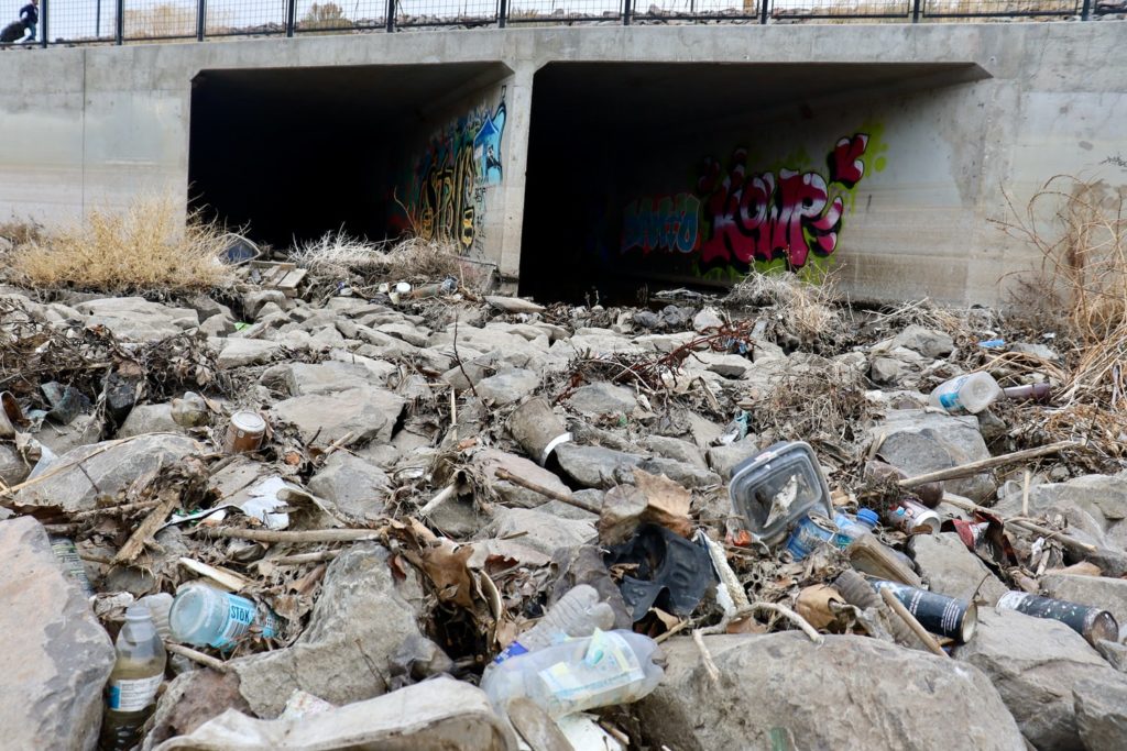 Litter strewn across sewer and rocks